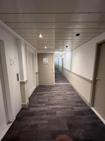 un couloir d'un immeuble de bureaux avec un long couloir dans l'établissement Appartement La Tania 2 pièces garage dans chalet pied pistes, à La Tania