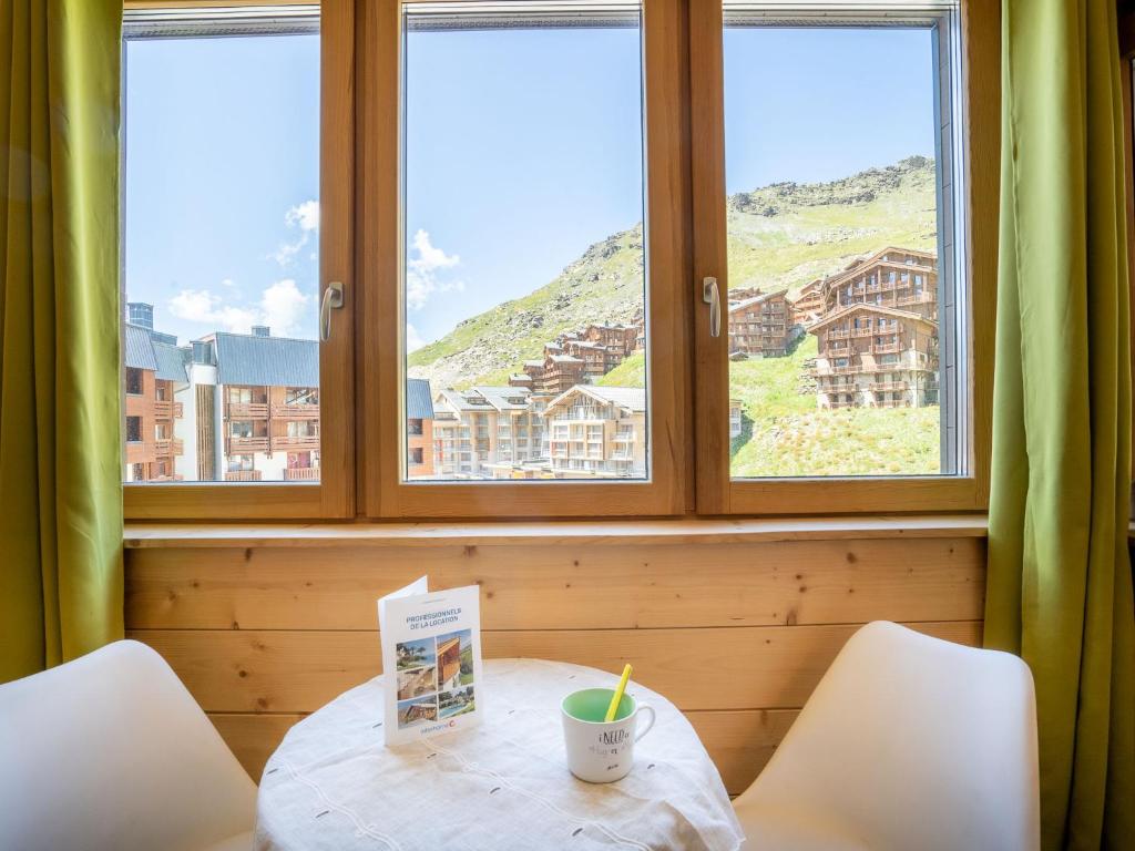 une table et des chaises dans une pièce avec des fenêtres dans l'établissement Studio Arcelle 216 by Interhome, à Val Thorens