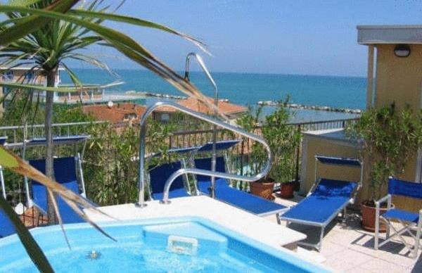 une piscine avec des chaises bleues et l'océan dans l'établissement Hotel Nordic, à Bellaria-Igea Marina