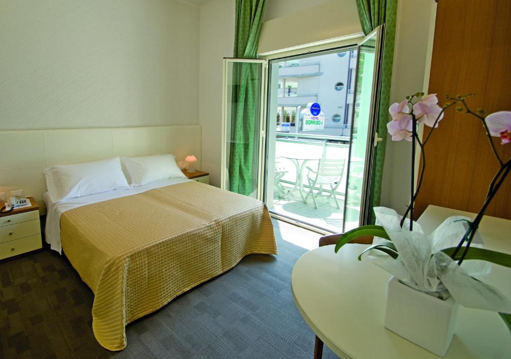une chambre d'hôtel avec un lit, une table et une fenêtre dans l'établissement Hotel Sorriso, à Milano Marittima