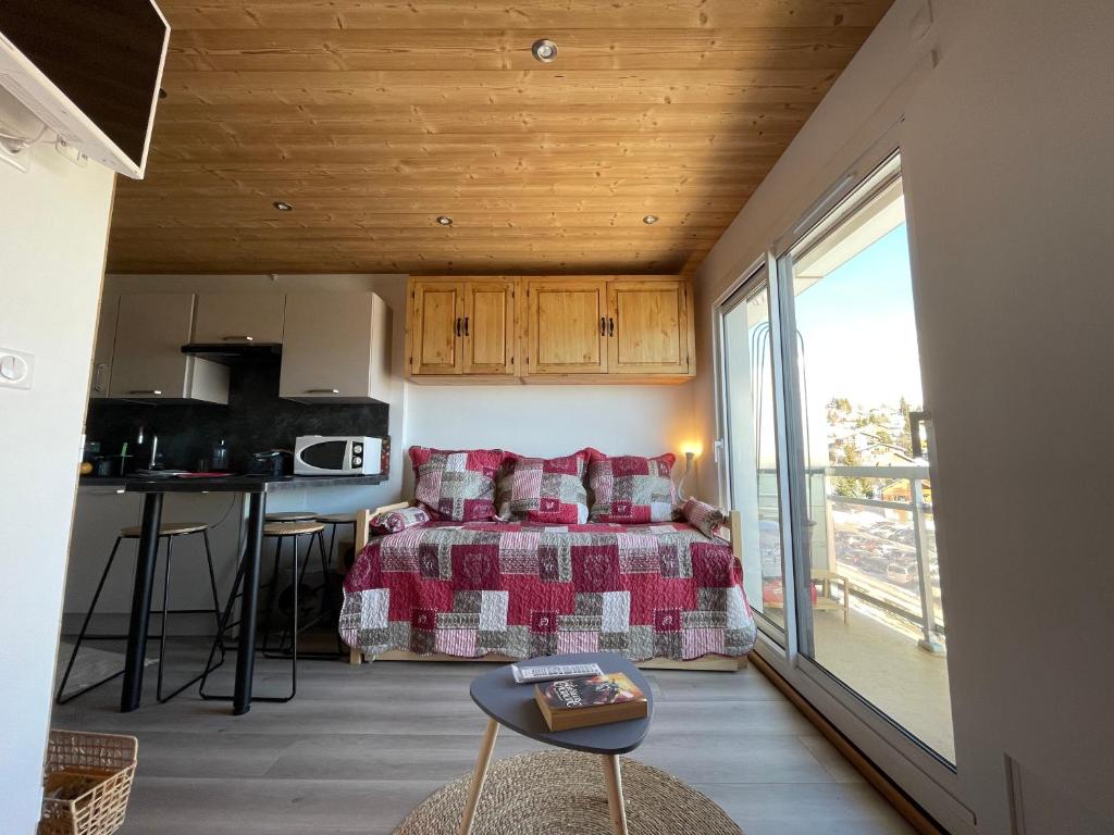 Cet appartement comprend une chambre avec un lit et une cuisine avec un balcon. dans l'établissement residence les Ravieres 1, à La Toussuire