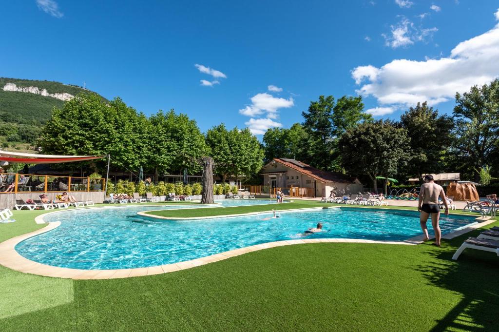 un homme debout à côté d'une piscine dans l'établissement Camping maeva Escapades Millau Plage, à Millau