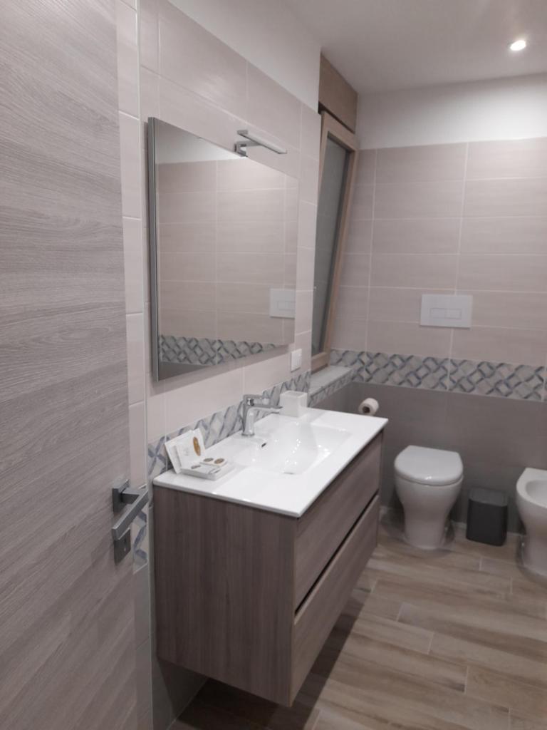 une salle de bain avec un lavabo, des toilettes et un miroir dans l'établissement Tripepi suites, à Reggio de Calabre