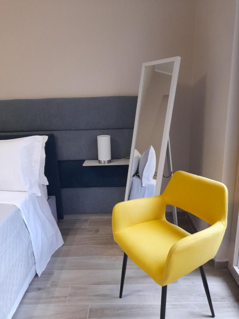 - une chambre avec une chaise jaune et un miroir dans l'établissement Tripepi suites, à Reggio de Calabre