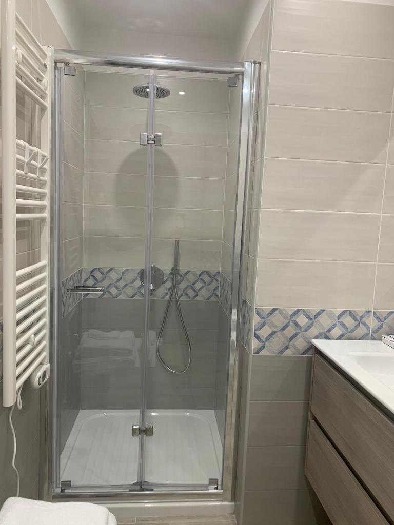 une douche avec une porte vitrée dans une salle de bain dans l'établissement Tripepi suites, à Reggio de Calabre