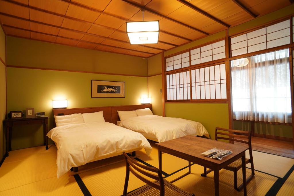 une chambre avec deux lits et une table dans l'établissement Arima Onsen Tocen Goshobo, à Kobe