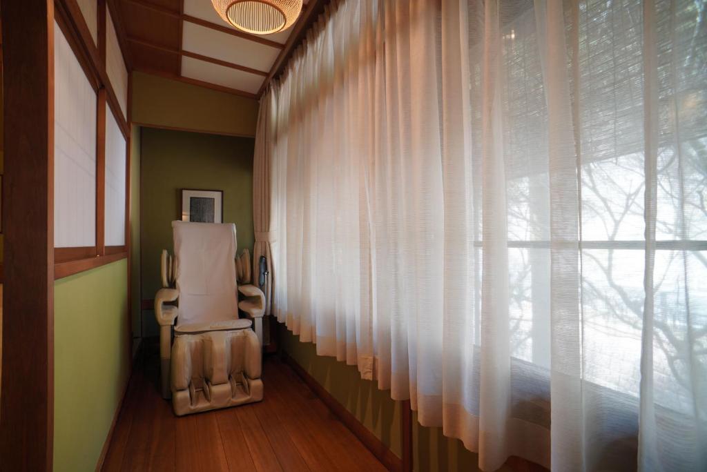 une chambre avec une chaise à côté d'une fenêtre dans l'établissement Arima Onsen Tocen Goshobo, à Kobe
