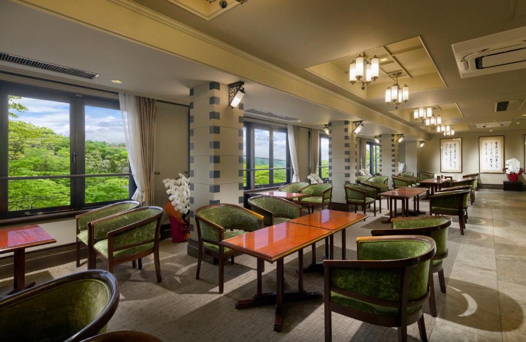 un restaurant avec des tables, des chaises et des fenêtres dans l'établissement Kishigon Ryokan, à Shibukawa