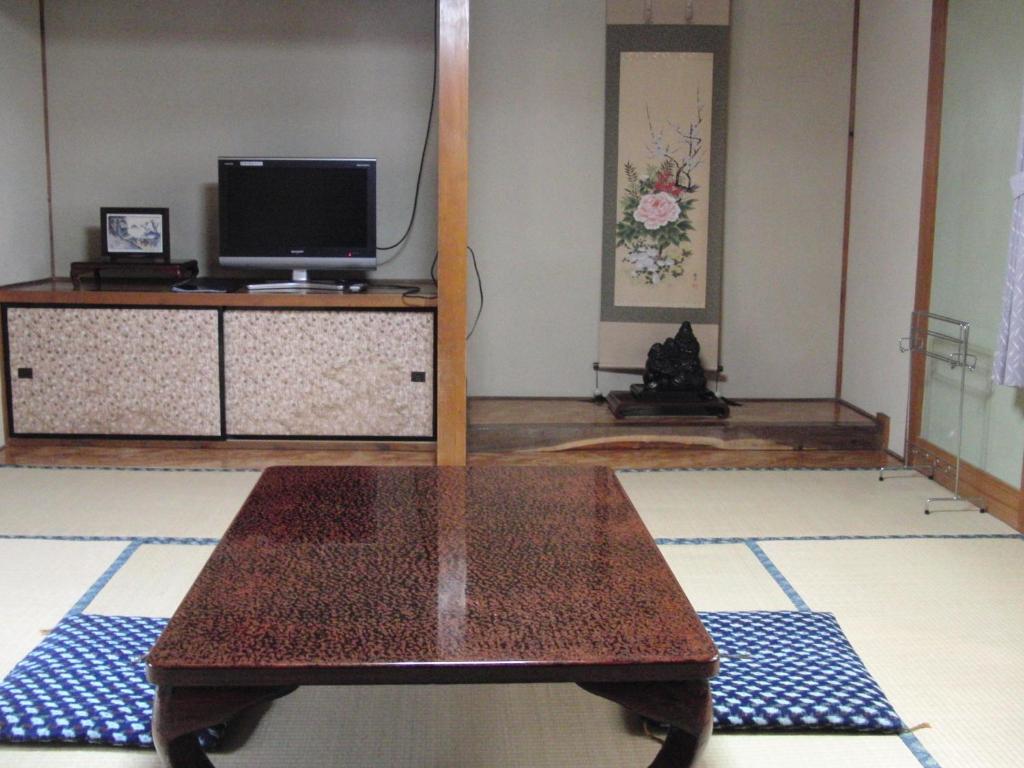 un salon avec une table et une télévision dans l'établissement Tajimaya, à Nakatsugawa