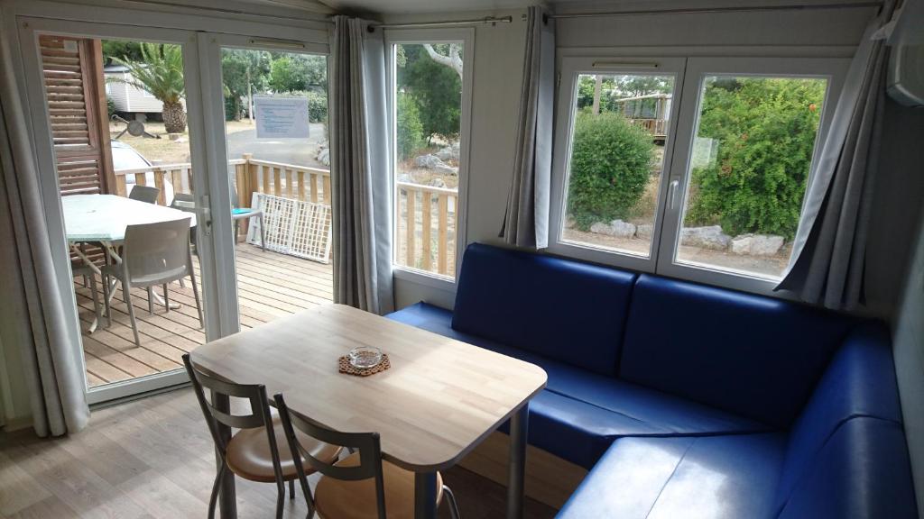 un salon avec un canapé bleu et une table dans l'établissement MOBIL HOME 4 PERSONNES TOUT CONFORT, à Port-la-Nouvelle
