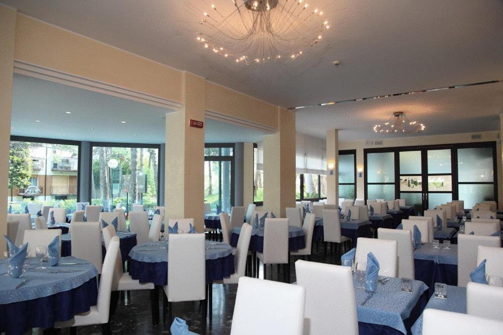 une salle de banquet avec des tables bleues et des chaises blanches dans l'établissement Hotel Bellevue, à Lignano Sabbiadoro 100 autres photos