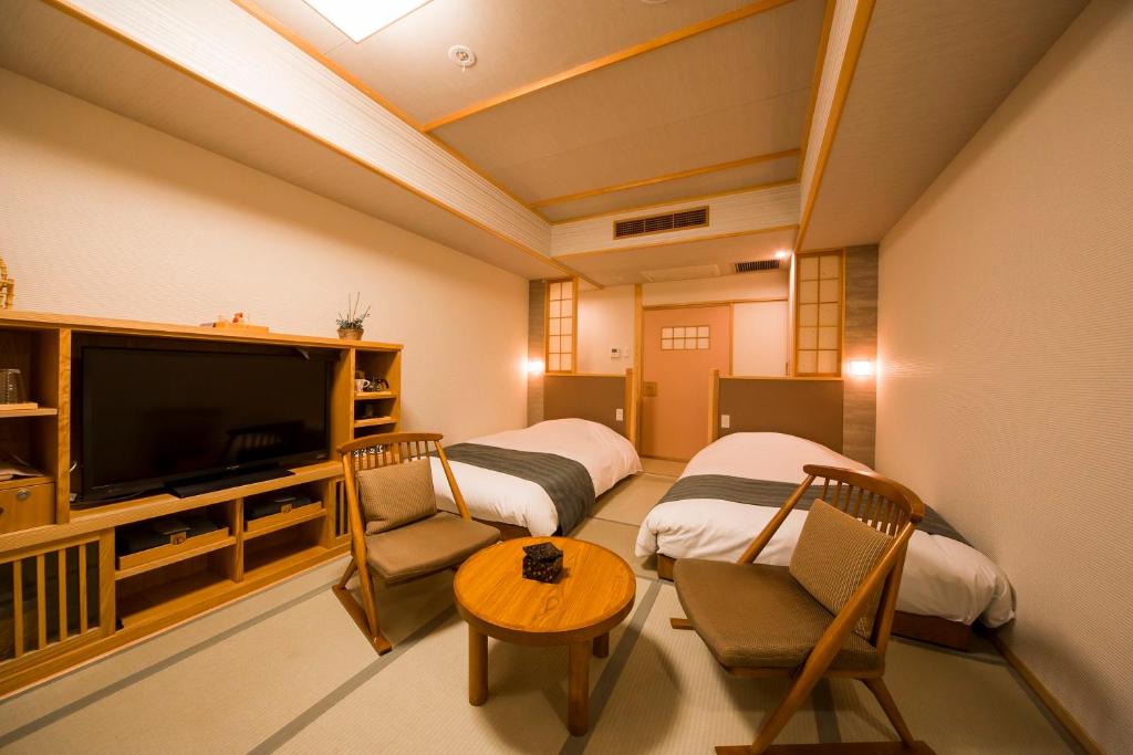 une chambre avec deux lits et une télévision à écran plat dans l'établissement Ikyu, à Ise