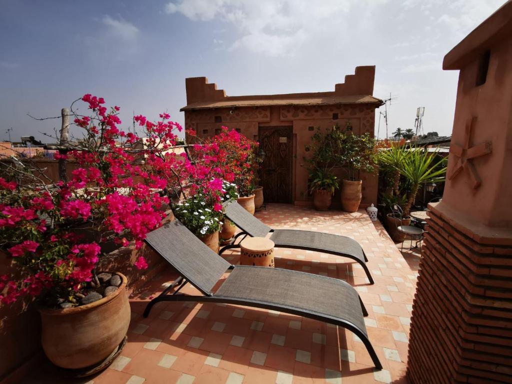 - un ensemble de chaises assises sur une terrasse fleurie dans l'établissement Riad Mehdia, à Marrakech