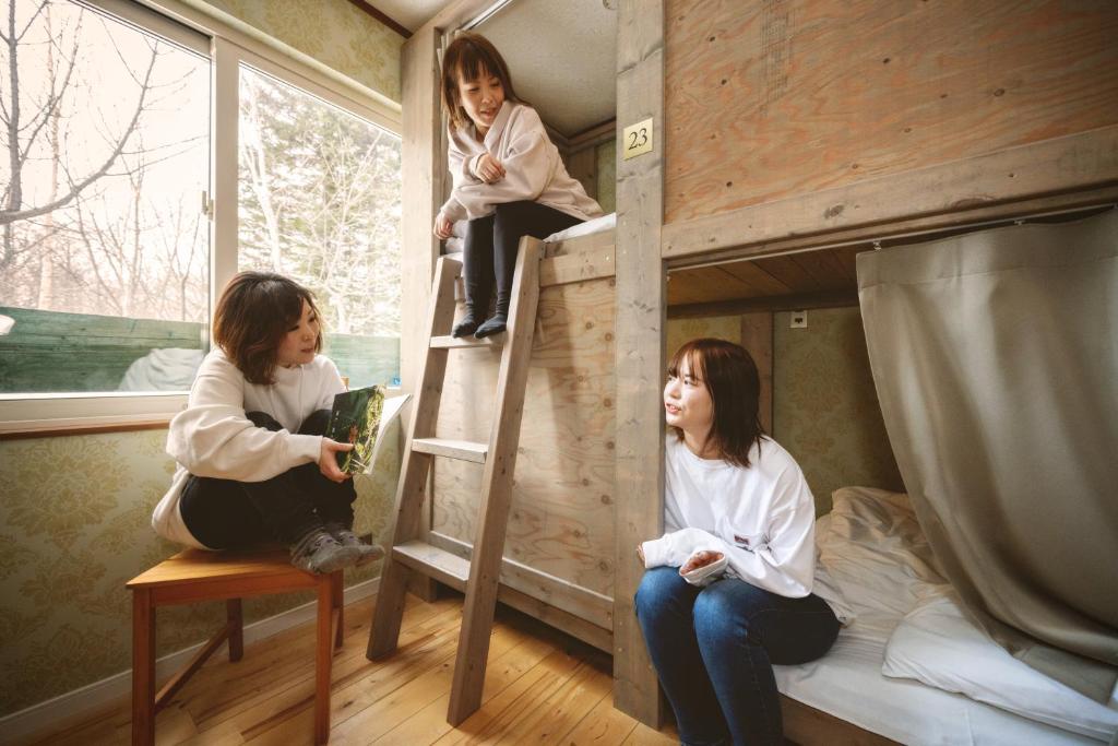 2 filles assises sur les escaliers d'un lit superposé dans l'établissement Shiretoko Village, à Shari