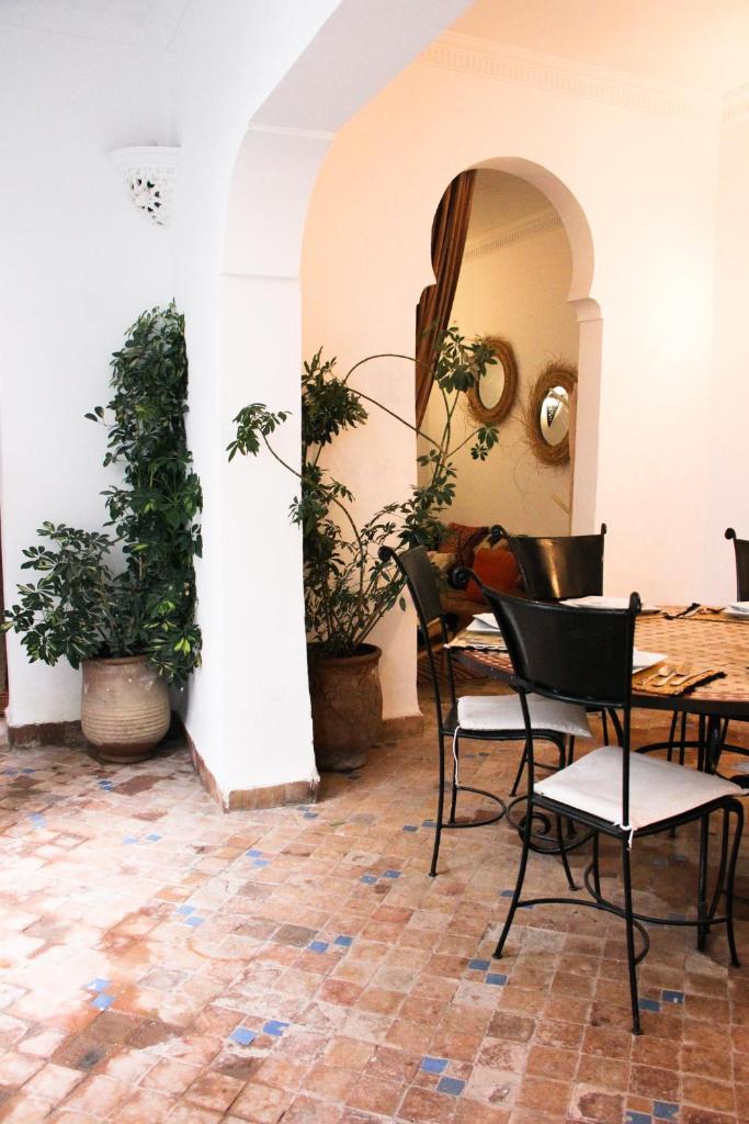 une table et des chaises dans une pièce avec des plantes dans l'établissement Riad Al Tainam, à Marrakech