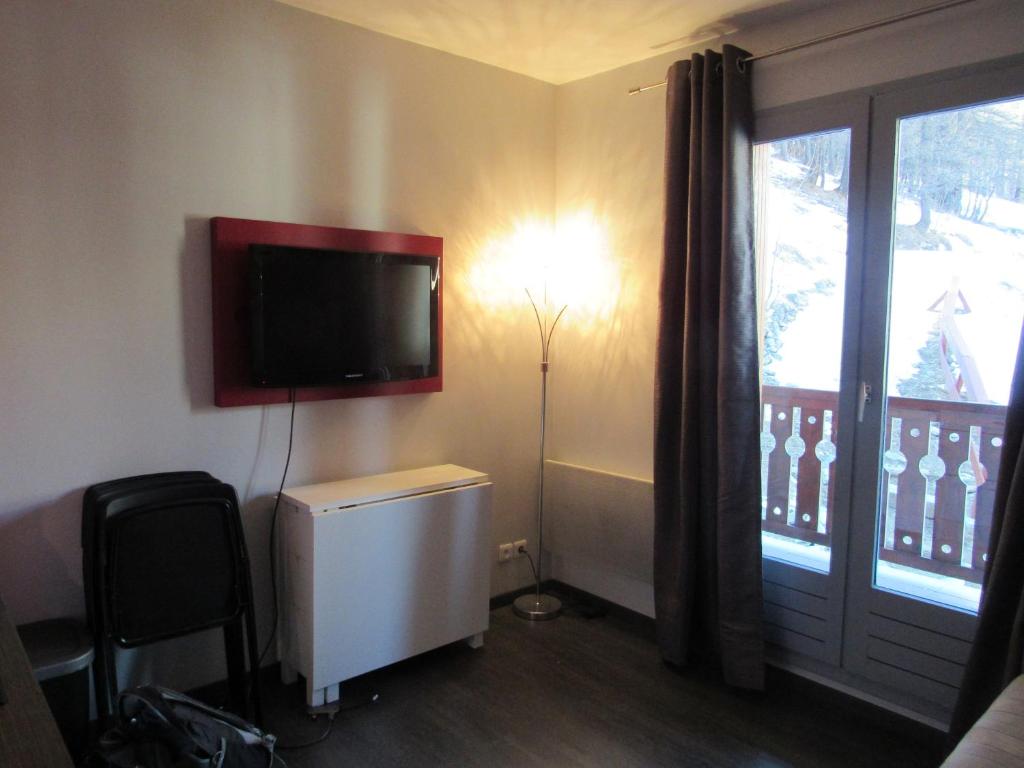 Cette chambre dispose d'une télévision murale et d'une fenêtre. dans l'établissement studio moderne avec coin montagne la vallée blanche 2 La Foux d Allos, à La Foux