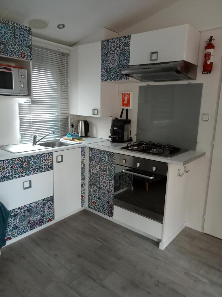 une cuisine avec des armoires blanches et un four à plaques de cuisson dans l'établissement Mobile Home Service Hotelier, à Fréjus