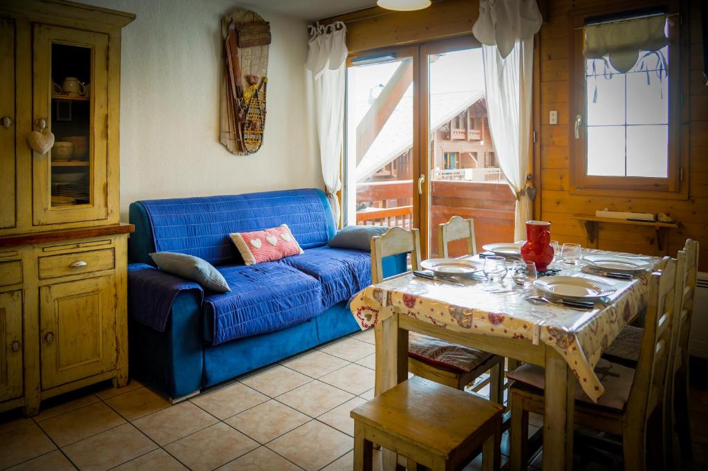 un salon avec une table et un canapé bleu dans l'établissement T2 Meublé Tourisme 3 etoiles, pied des pistes-parking privé avec balcon et superbe vue, à Les Deux Alpes