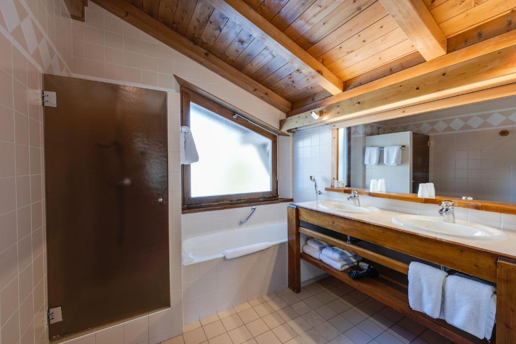 une salle de bain avec une baignoire et un lavabo et une baignoire dans l'établissement Hôtel La Grange d'Arly, à Megève 34 autres photos