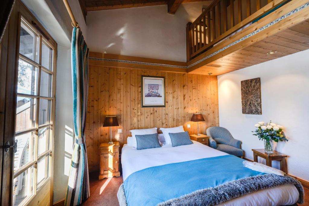 - une chambre avec un grand lit et un mur en bois dans l'établissement Hôtel La Grange d'Arly, à Megève