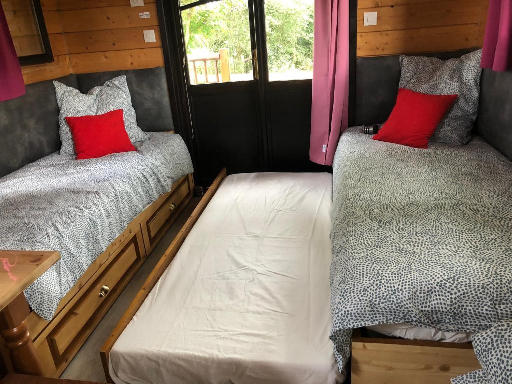 - 2 lits dans une petite maison avec des oreillers rouges dans l'établissement Roul'hôtes évasion, à Clamerey