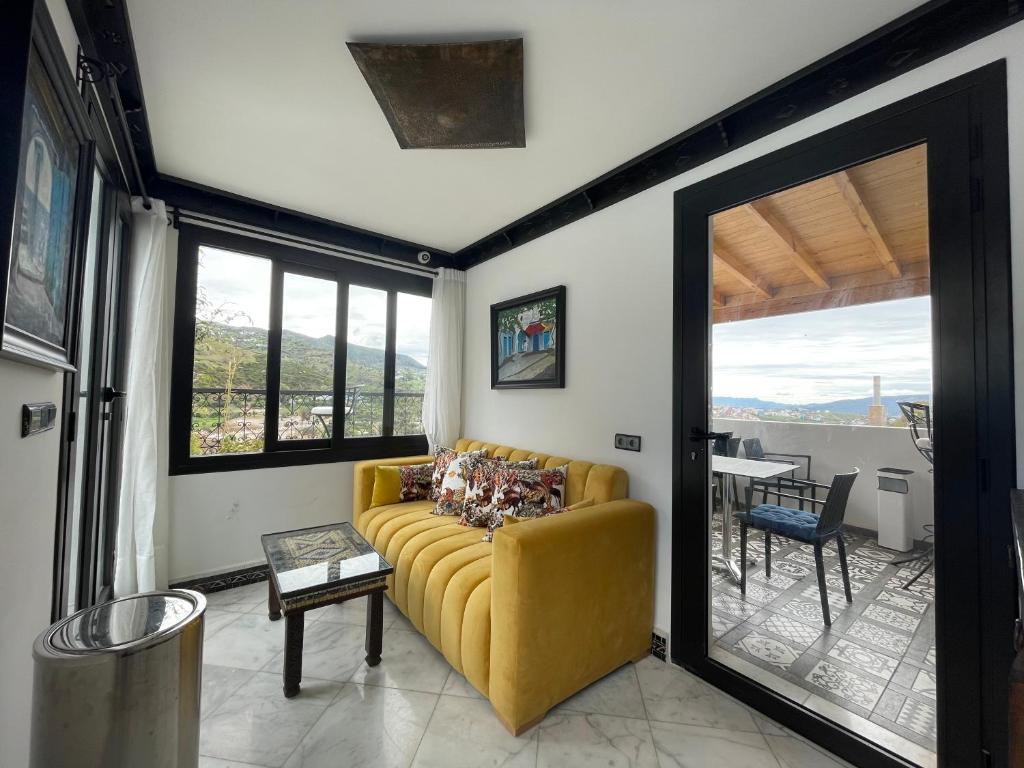 un salon avec un canapé jaune et une table dans l'établissement Riad El Palacio & Spa Chaouen, à Chefchaouen