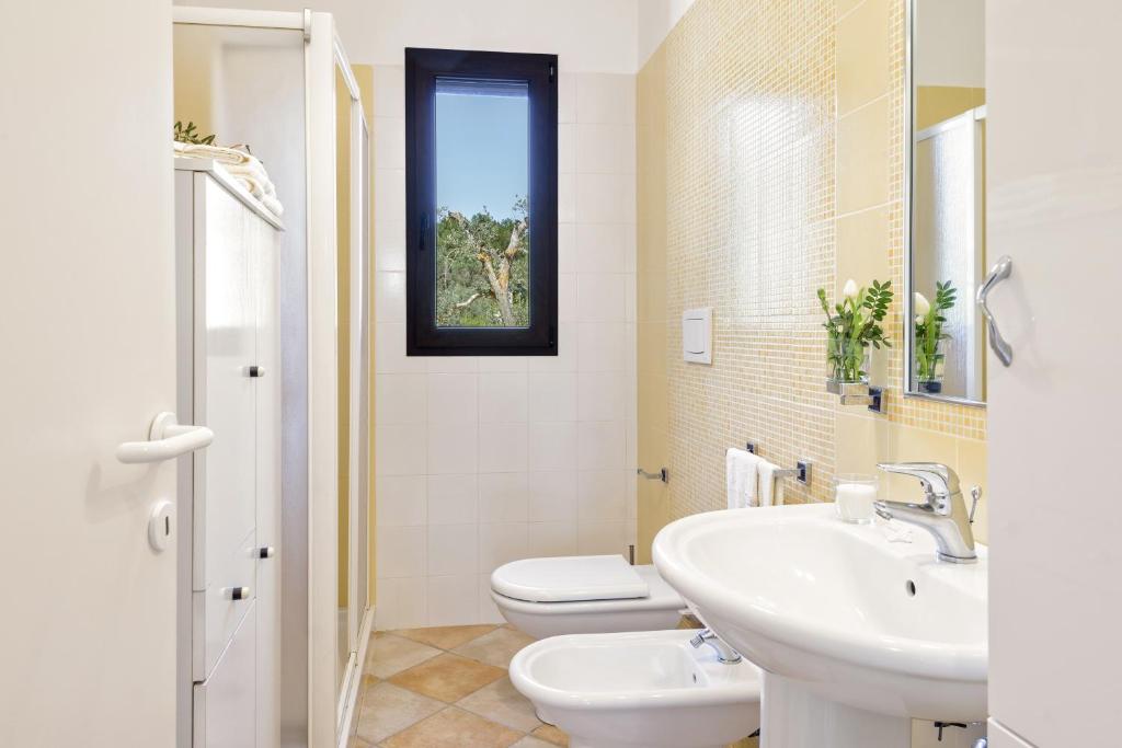 une salle de bain avec un lavabo et des toilettes et une fenêtre dans l'établissement Villa Käthe con Piscina Privata, à San Vito dei Normanni 21 autres photos