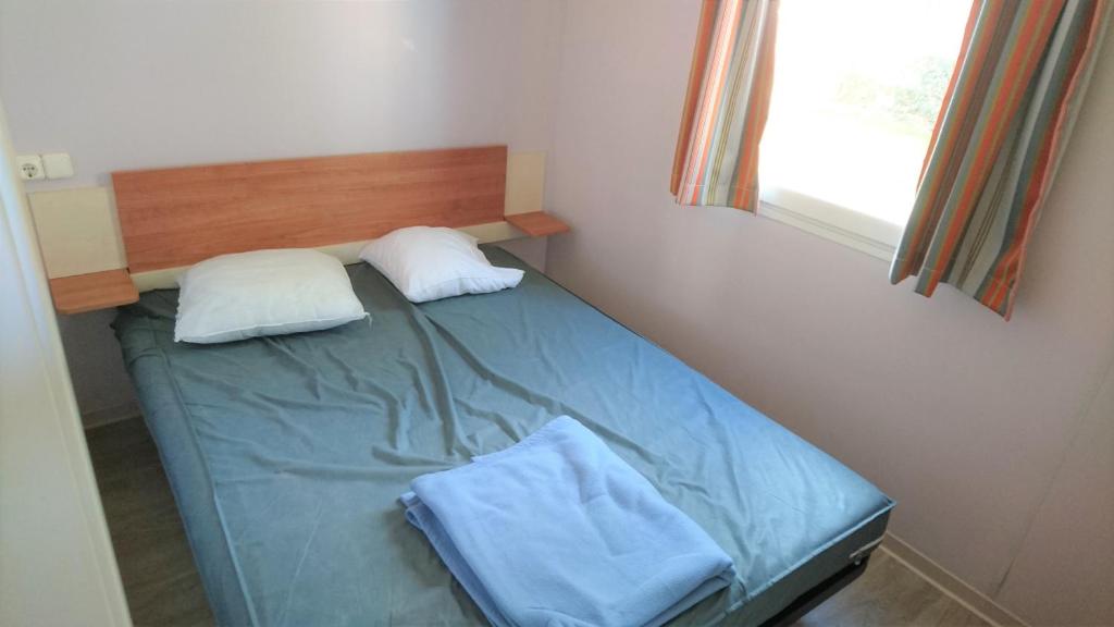 - un petit lit dans une chambre avec 2 oreillers dans l'établissement Mobil home 6 personnes PORT LA NOUVELLE, à Port-la-Nouvelle