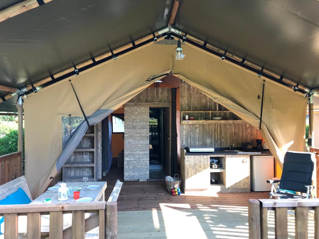 une tente avec une table et des chaises ainsi qu'une cuisine dans l'établissement Safaritent Glamping L'Ardechois, à Gluiras