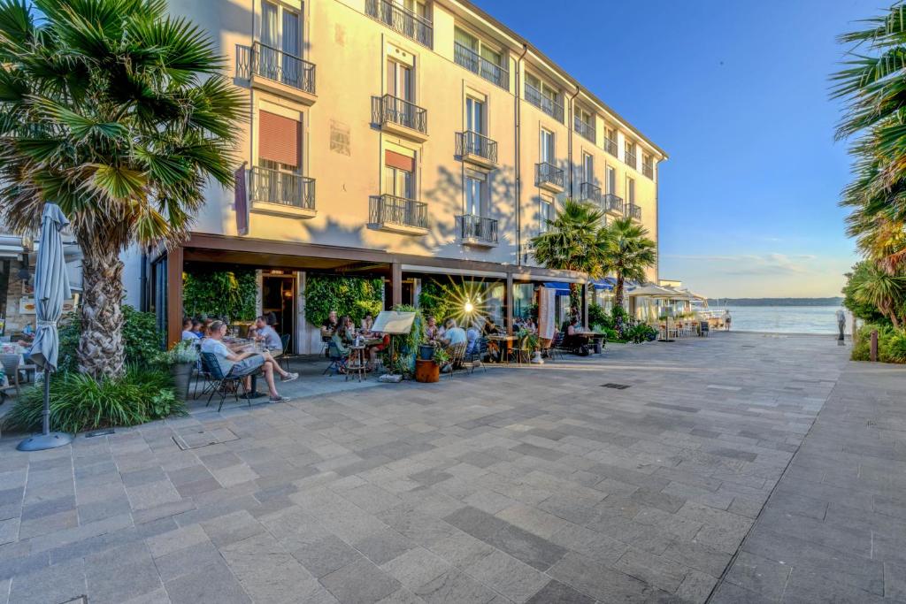 un groupe de personnes assises à l'extérieur d'un bâtiment dans l'établissement Hotel Flaminia, à Sirmione