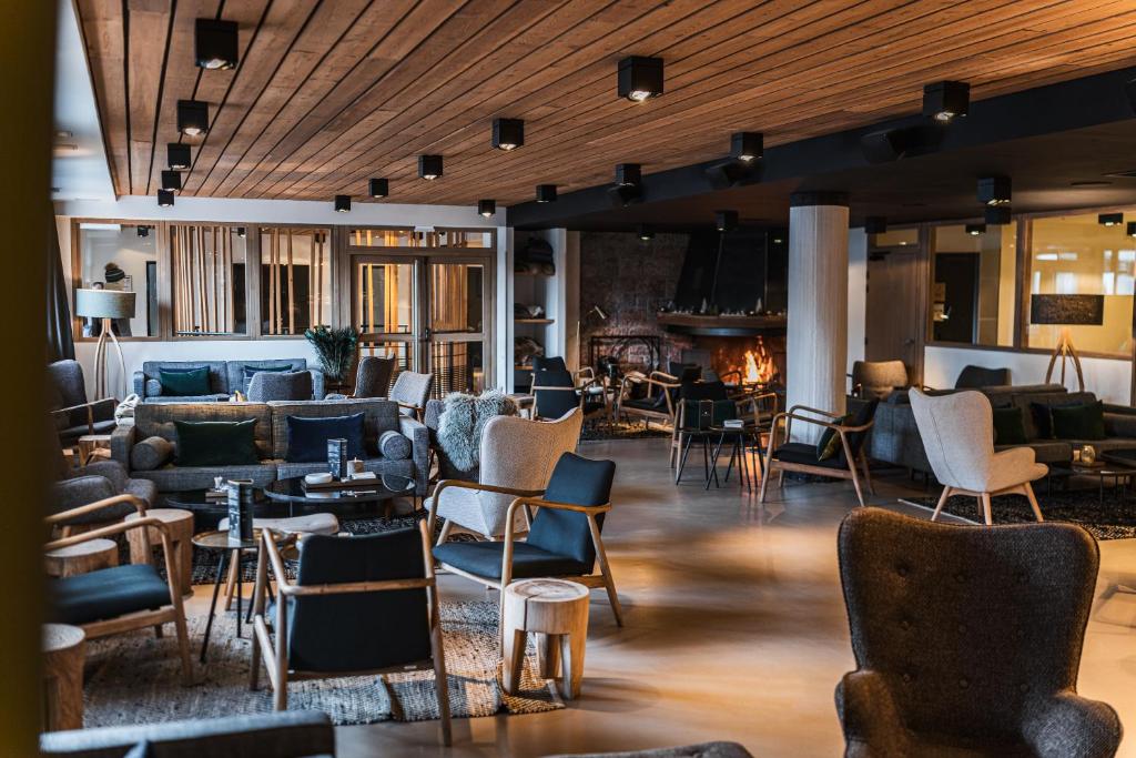 - un hall avec des chaises, des tables et une cheminée dans l'établissement Grand Hôtel & Spa NUXE Serre Chevalier, à Saint-Chaffrey