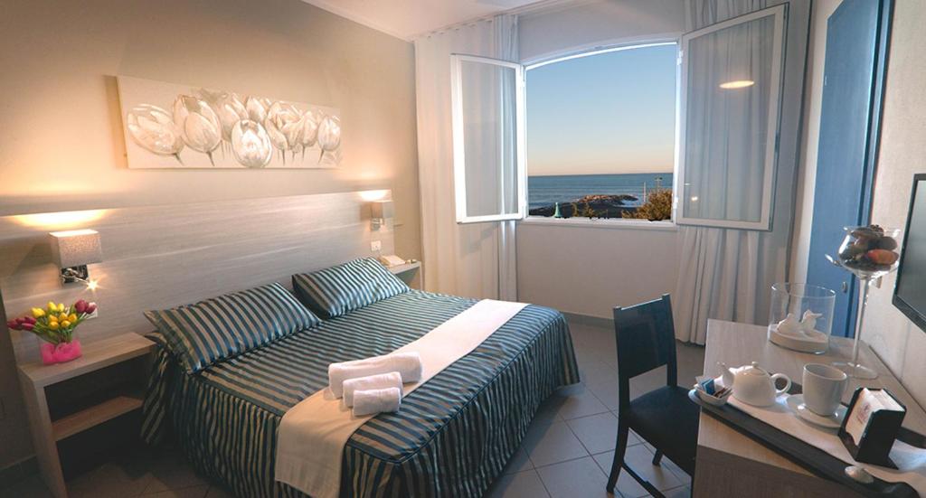une chambre avec un lit, un bureau et une fenêtre dans l'établissement HG Hotel Il Settebello, à Marina di Cecina