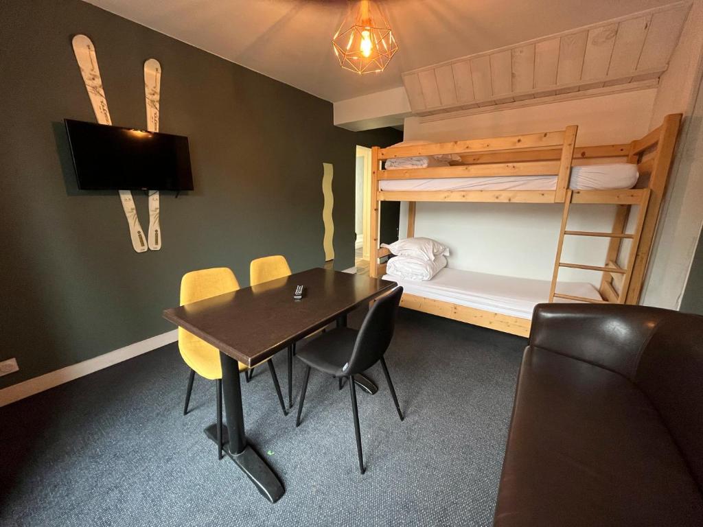 une chambre avec une table, des chaises et un lit superposé dans l'établissement Le Rocher Du Cerf, à Le Lioran