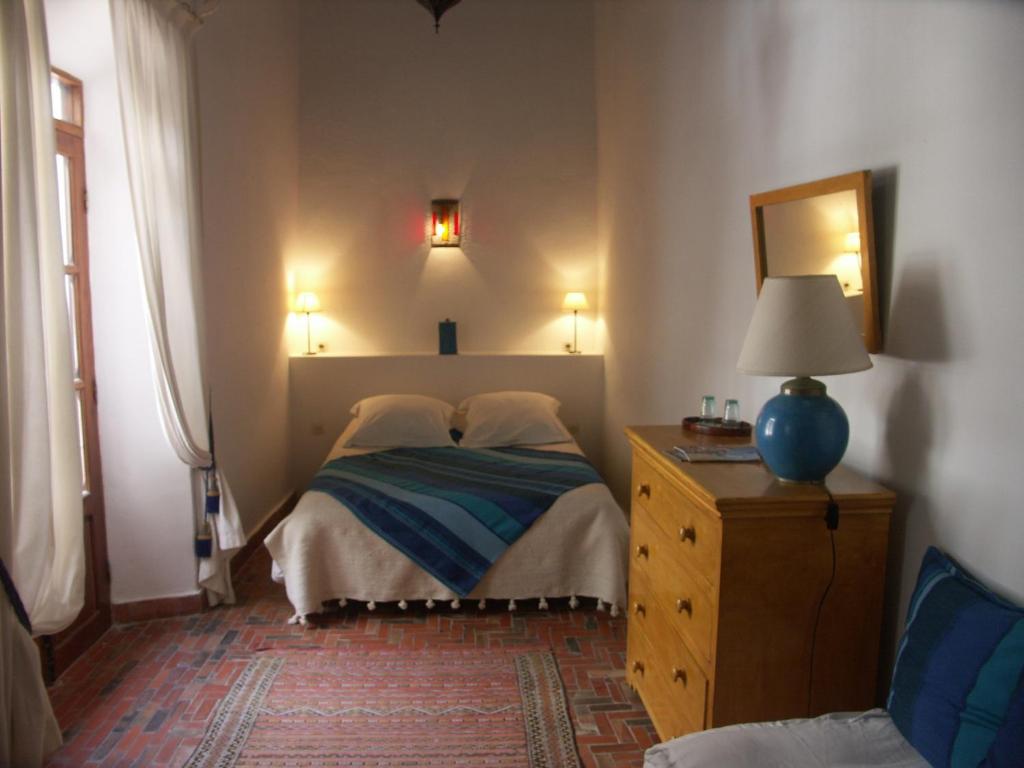 - une chambre avec un lit avec un miroir et une commode dans l'établissement Dar Ness, à Essaouira