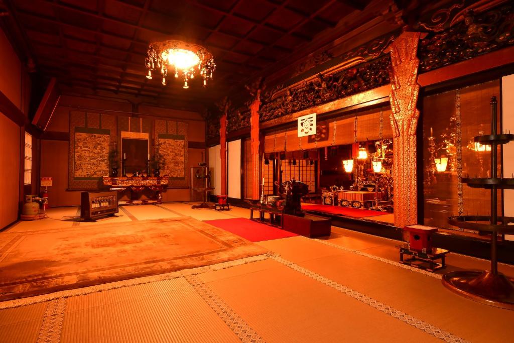 un salon avec un lustre et une grande chambre avec une table dans l'établissement 高野山 宿坊 龍泉院 -Koyasan Shukubo Ryusenin-, à Koyasan