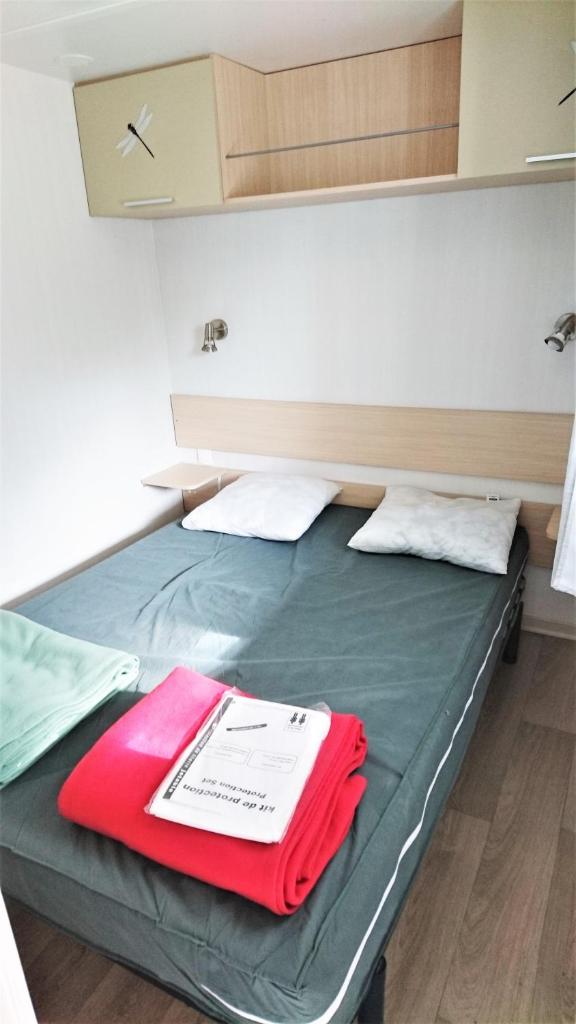 - un lit avec une couverture rouge dans l'établissement MOBIL HOME 4 PERSONNES TOUT CONFORT, à Port-la-Nouvelle