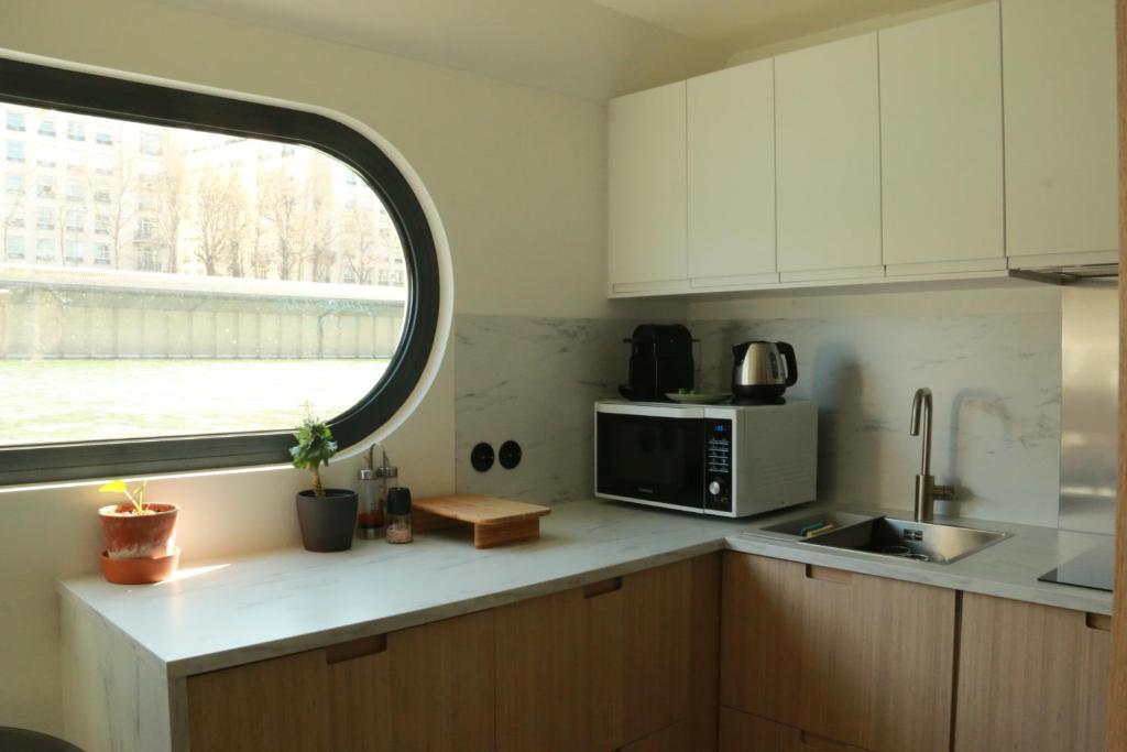 La cuisine est équipée d'une fenêtre et d'un four micro-ondes. dans l'établissement Studio très cosy - indépendant dans une péniche - Paris 16, à Puteaux
