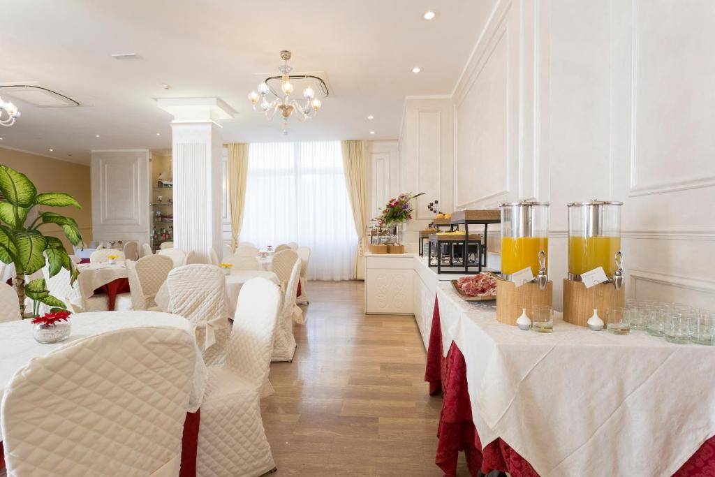 une salle à manger avec des tables blanches et des chaises blanches dans l'établissement Amsterdam Suite Hotel & SPA, à Rimini