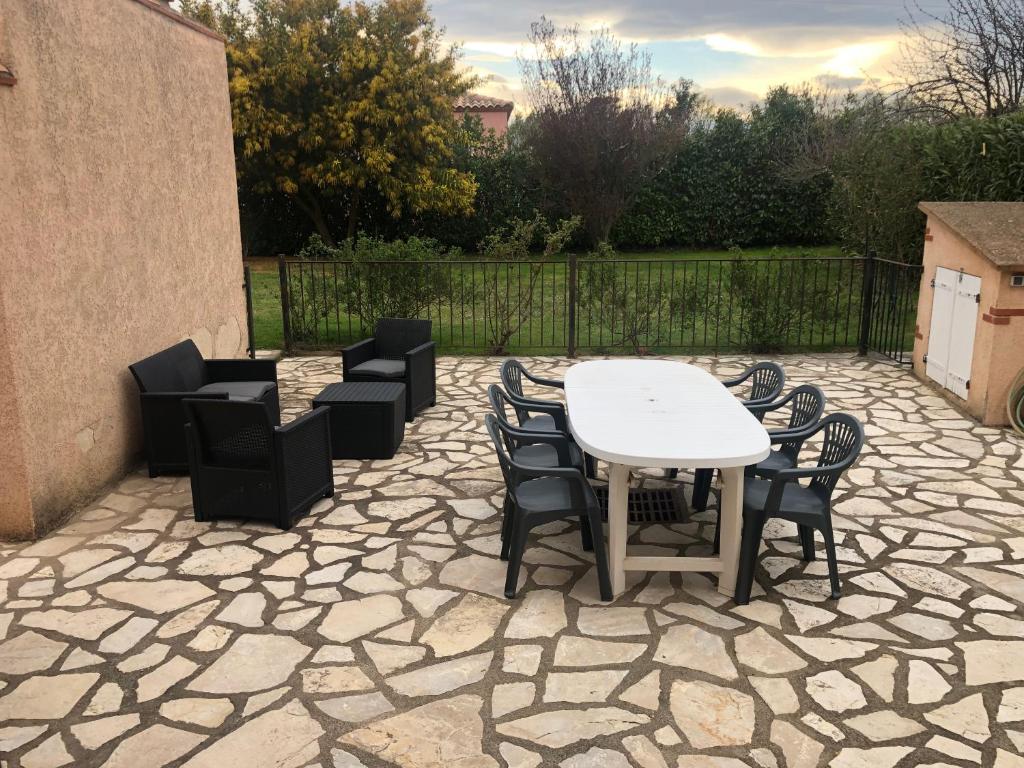 une terrasse en pierre avec une table et des chaises blanches dans l'établissement AU MIMOSA -Gîte Le Canigou, à Passa