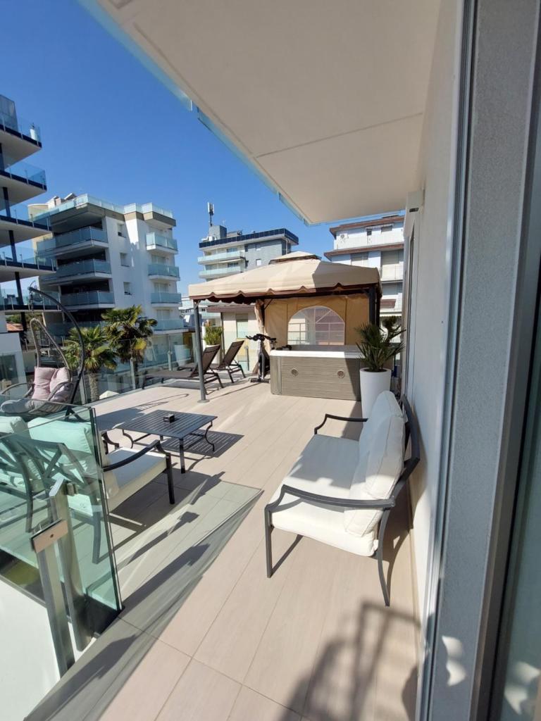 un balcon avec des chaises et des tables sur un immeuble dans l'établissement Hotel Rossini 4S, à Lignano Sabbiadoro