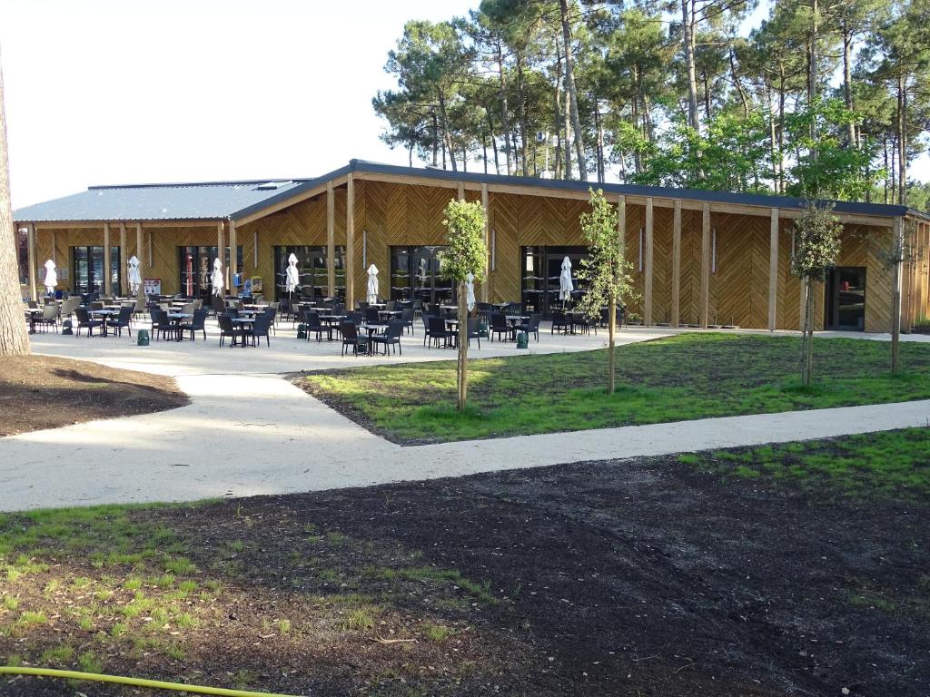 un bâtiment avec des tables et des chaises devant lui dans l'établissement Escape MobilHome aux Dunes de Contis, à Saint-Julien-en-Born