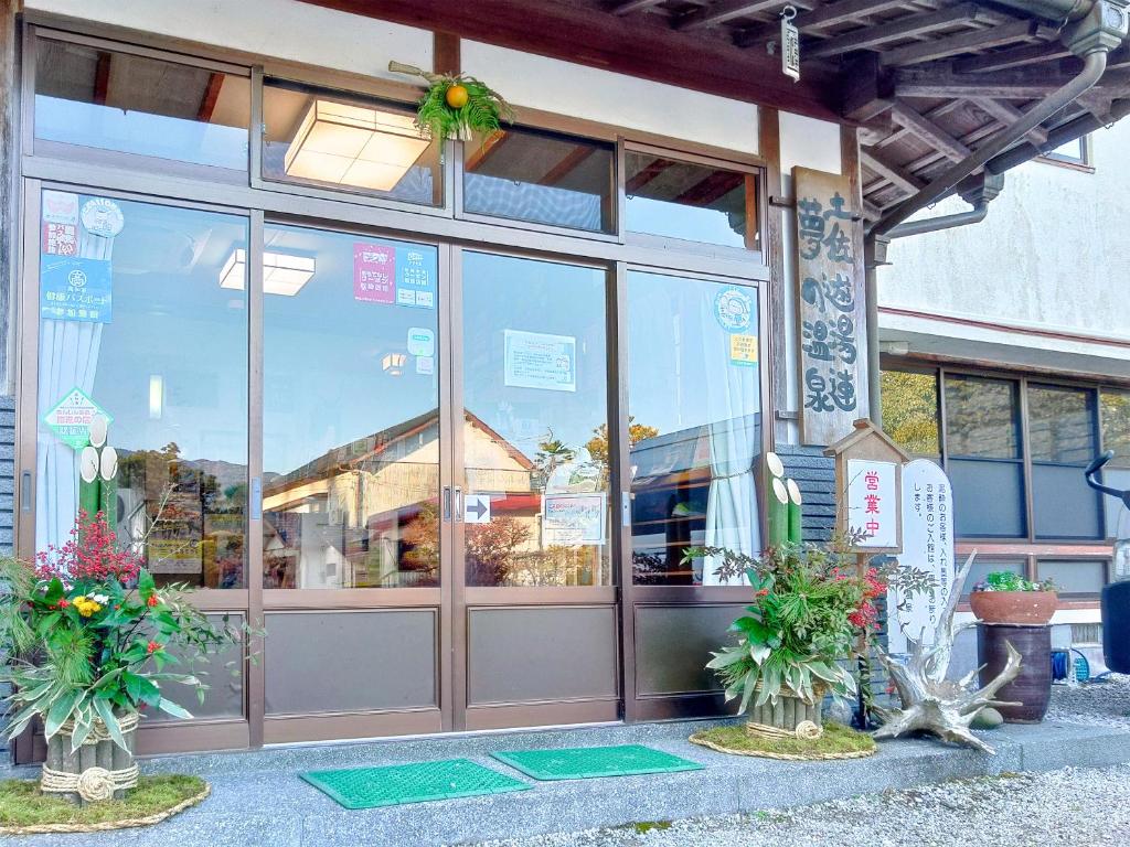 un front de magasin avec des plantes devant lui dans l'établissement Yumeno Onsen, à Kami