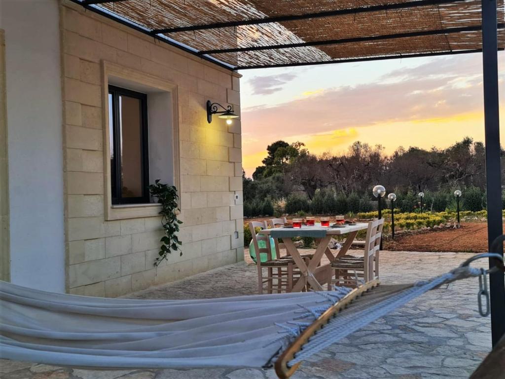 une terrasse avec une table et des chaises et un coucher de soleil dans l'établissement Villa Li Tratturi Luxury by HDSalento, à Corsano