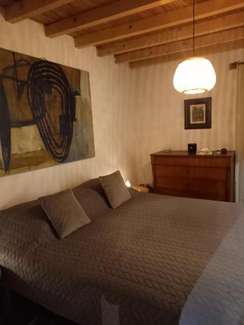une chambre avec un lit et un tableau au mur dans l'établissement Gite l' Embrassement le Luquet Saint Beauzeil 82, à Saint-Beauzeil