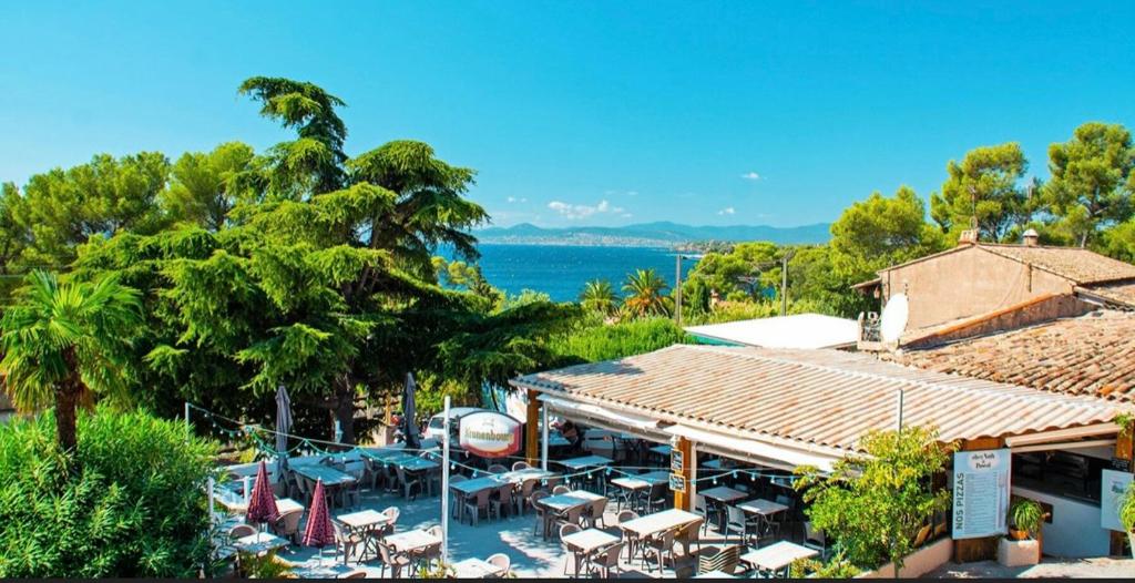 un complexe avec des tables et des chaises et l'océan dans l'établissement Mobil home 8 personnes camping l ile d or saint raphael, à Saint-Raphaël