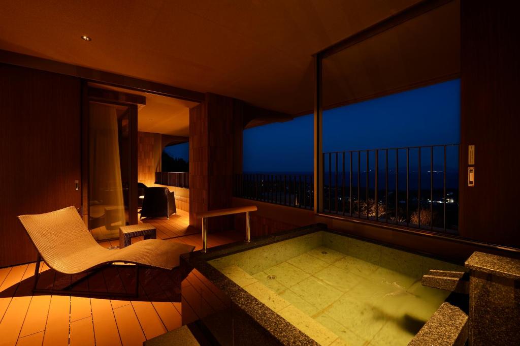Cette chambre dispose d'une baignoire, d'une chaise et d'une fenêtre. dans l'établissement KAMENOI HOTEL Izukogen, à Itō
