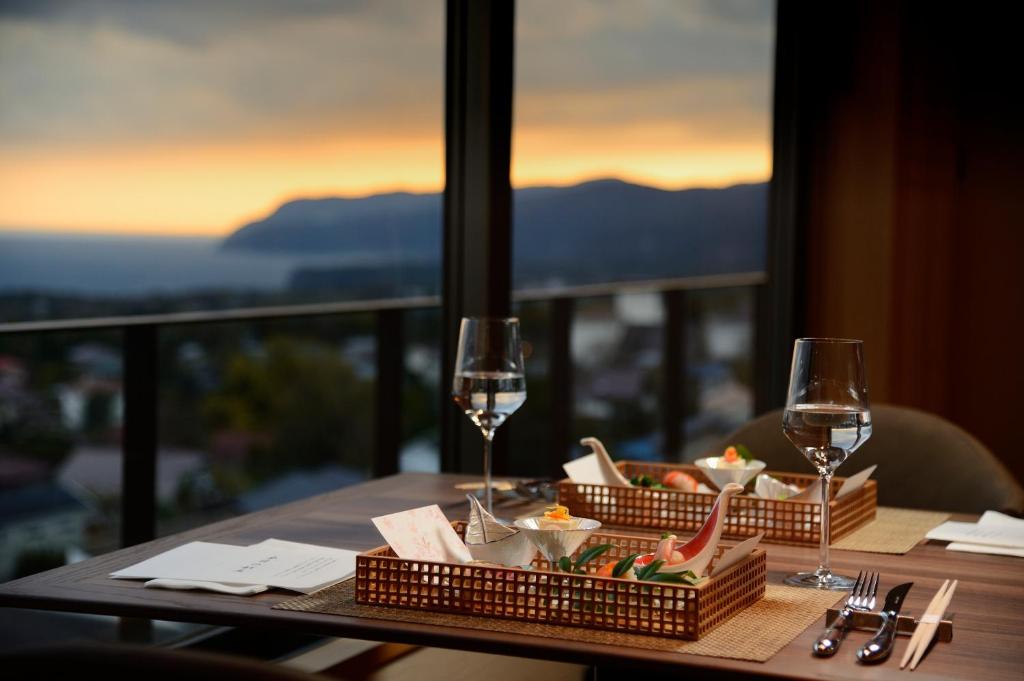 - une table avec deux verres de vin et de nourriture dans l'établissement KAMENOI HOTEL Izukogen, à Itō