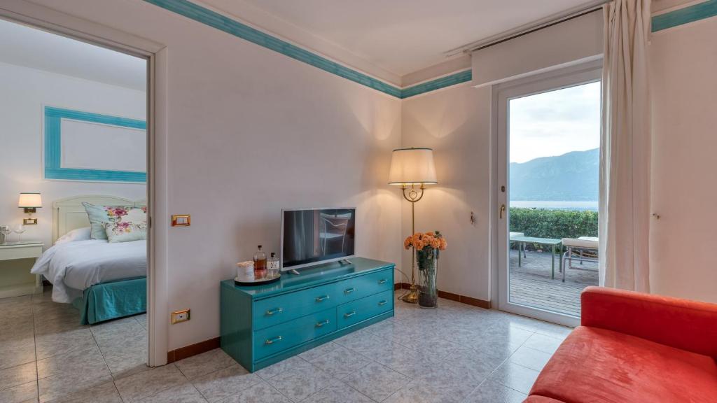 une chambre avec un lit, une télévision et une fenêtre dans l'établissement La Caletta Hotel Bolognese, à Brenzone