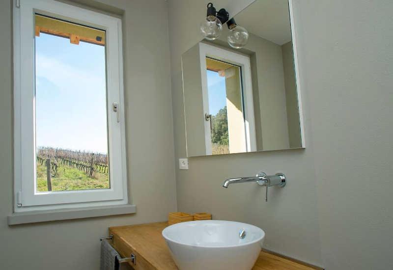 une salle de bain avec un lavabo, un miroir et une fenêtre dans l'établissement Villa Via Bolgherese, à Bibbona