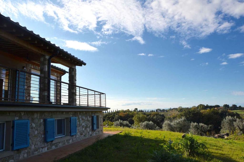 une maison en pierre avec des volets bleus et un champ dans l'établissement Villa Via Bolgherese, à Bibbona